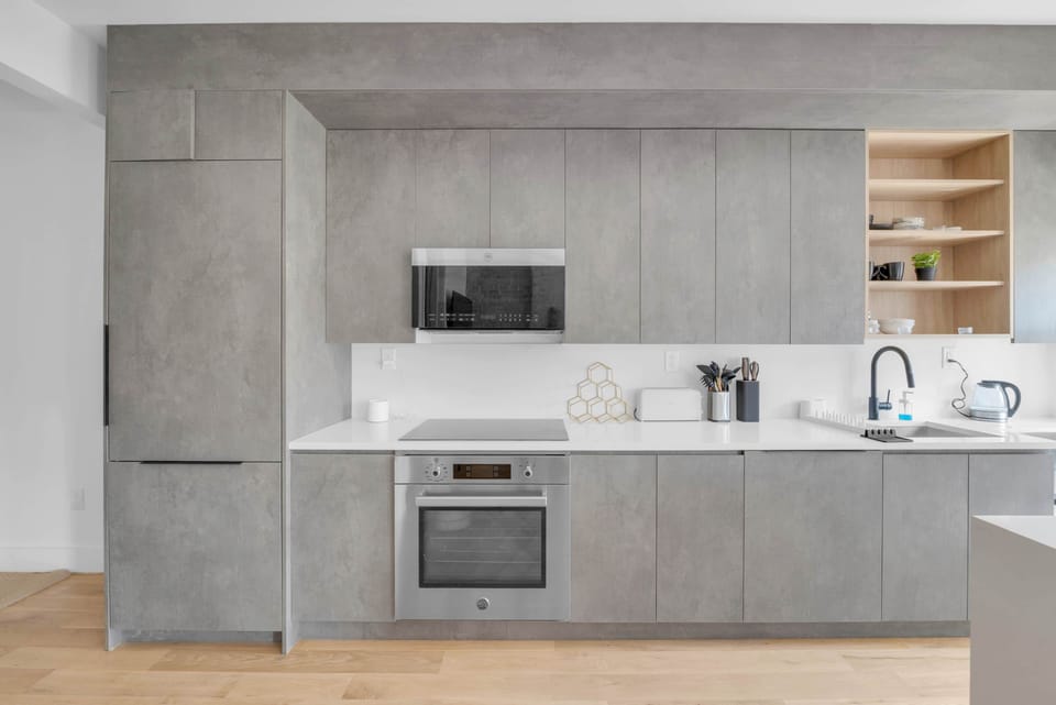 Sleek minimalist kitchen with gray cabinets, white counters, and appliances.