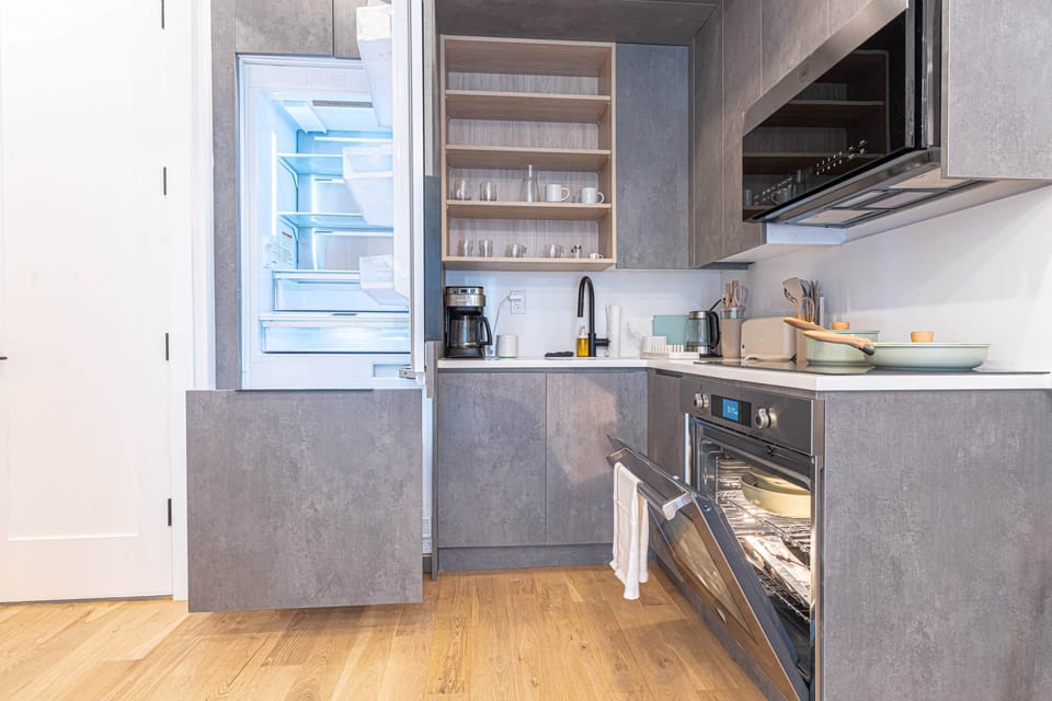 Modern kitchen with oven, large fridge, and fully equipped setup.