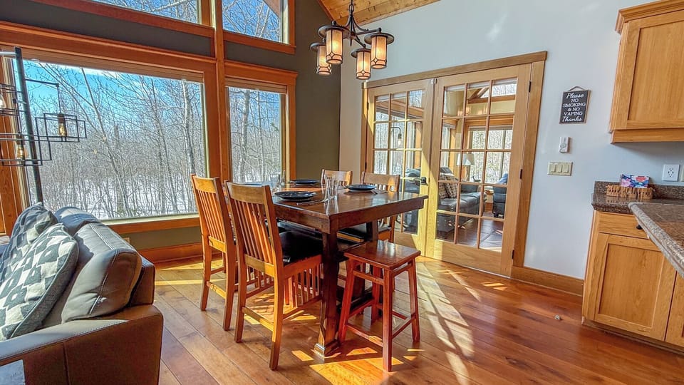 Gather for memorable meals in this warm dining space, where natural light streams through expansive windows and rich wood details create the perfect atmosphere for your getaway conversations.