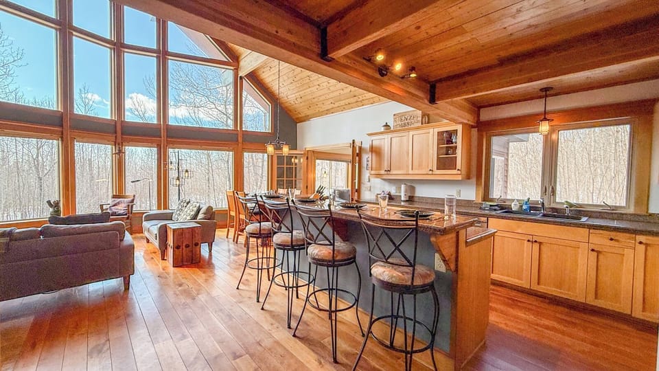 Soak in the warmth of this stunning open-concept space where soaring ceilings and floor-to-ceiling windows frame peaceful forest views.