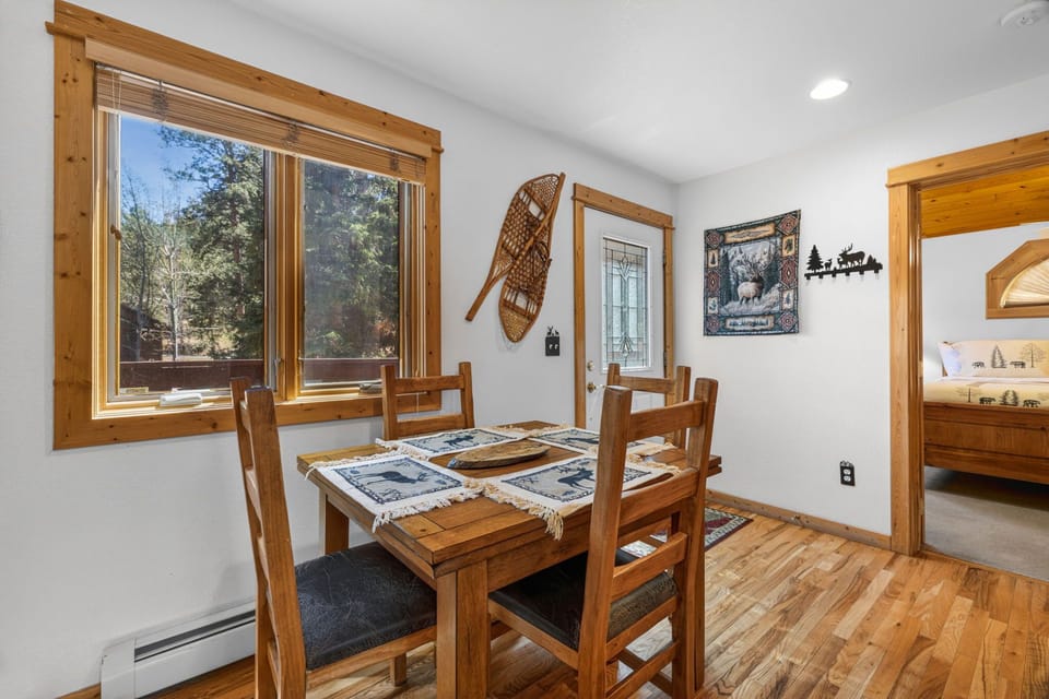 Gather around this rustic dining table where mountain charm meets comfort, perfect for sharing meals with forest views streaming through.