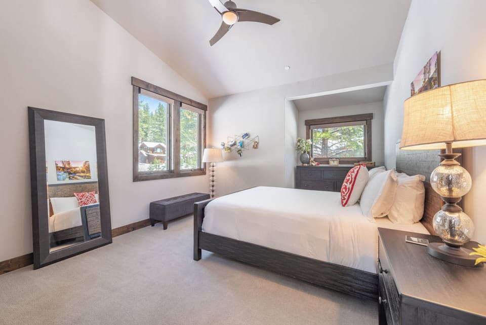 Unwind in your serene bedroom with crisp linens, elegant decor, and forest views through large windows.