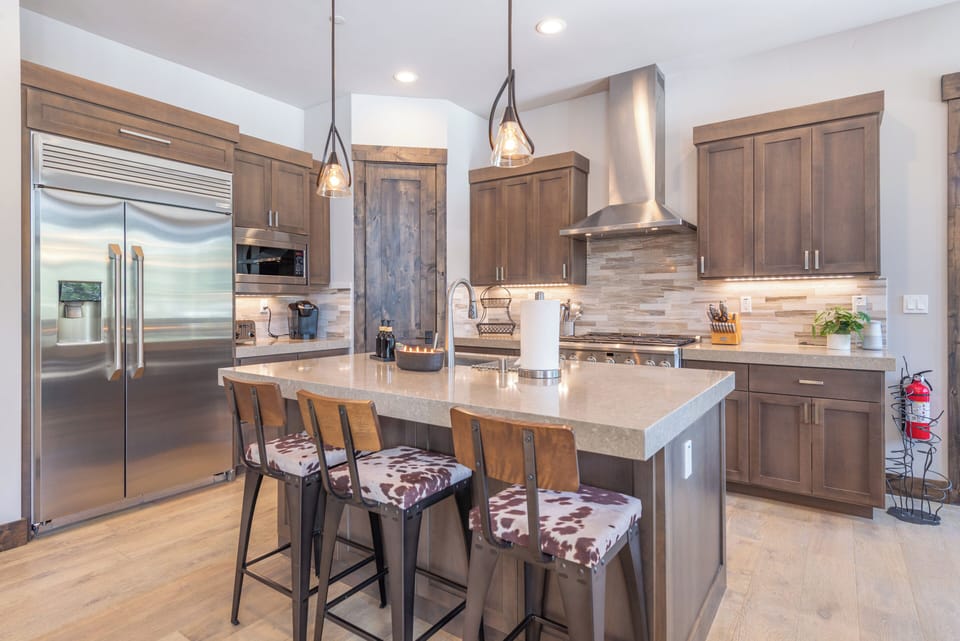 Your gourmet kitchen awaits with gleaming stainless appliances, warm wood cabinets, and a spacious island perfect for morning coffee or evening cocktails.