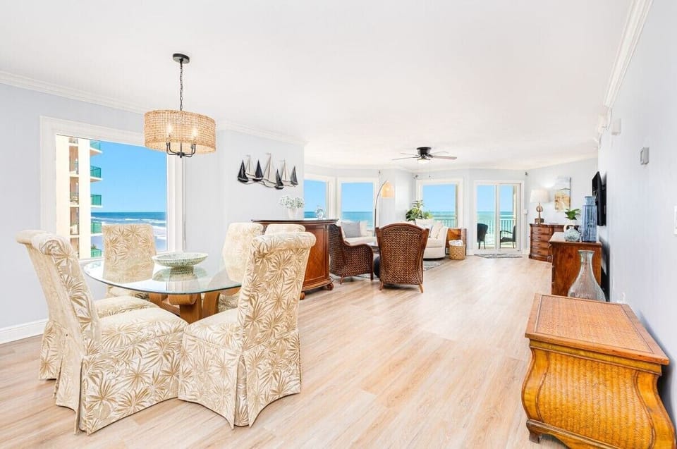 Dining room with living area and private oceanfront balcony in the background.