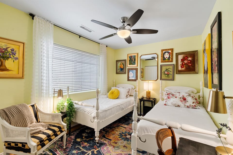 A bright and inviting secondary bedroom features two twin beds dressed in premium linens. Ample natural light and dedicated closet space, it is a quiet, comfortable retreat perfectly suited for family, friends, or colleagues.