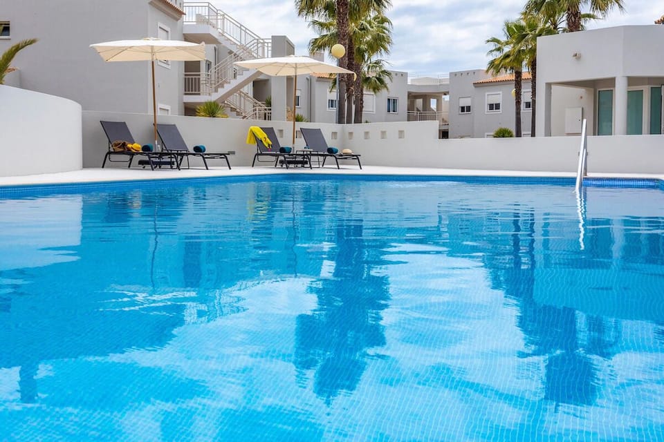Lounge poolside on cushioned chairs beneath cooling umbrellas.