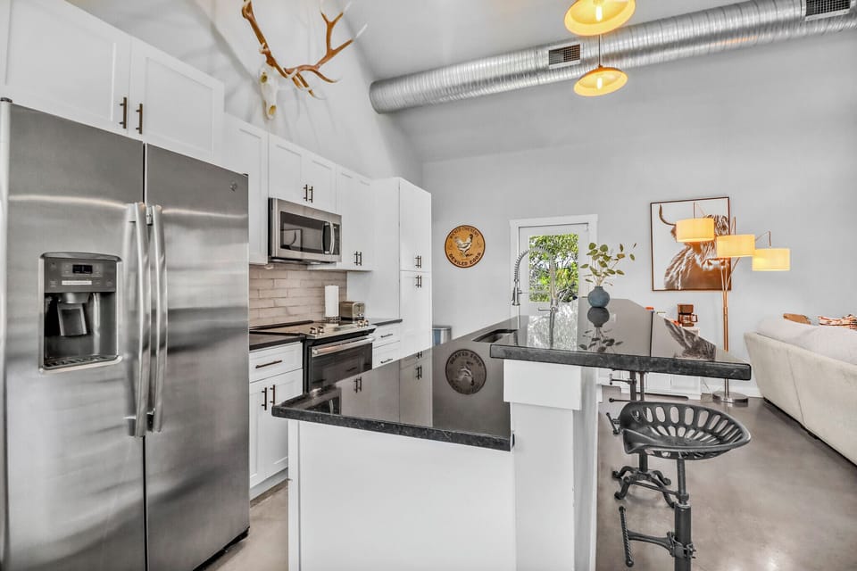 Your sleek modern kitchen awaits with stainless steel appliances, granite countertops, and stylish seating perfect for morning coffee or casual meals.