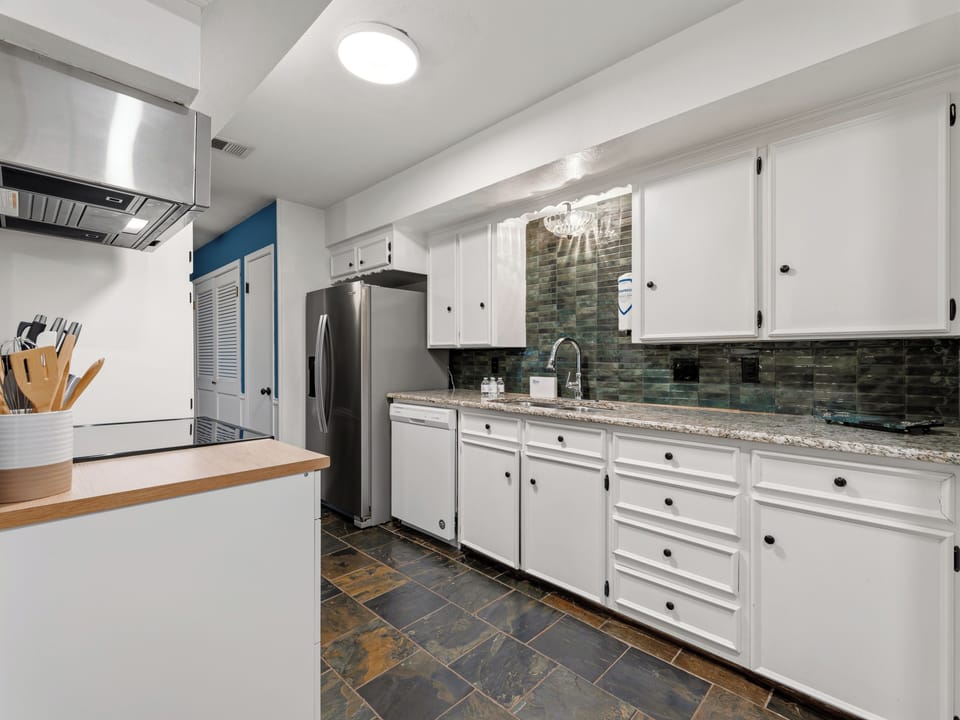 Your fully-equipped kitchen features granite countertops, white cabinets, and stainless steel appliances, perfect for preparing memorable meals together.