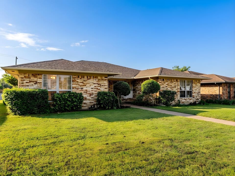 A beautiful brick ranch-style home welcomes guests with manicured lawns and landscaped grounds in a peaceful residential setting.