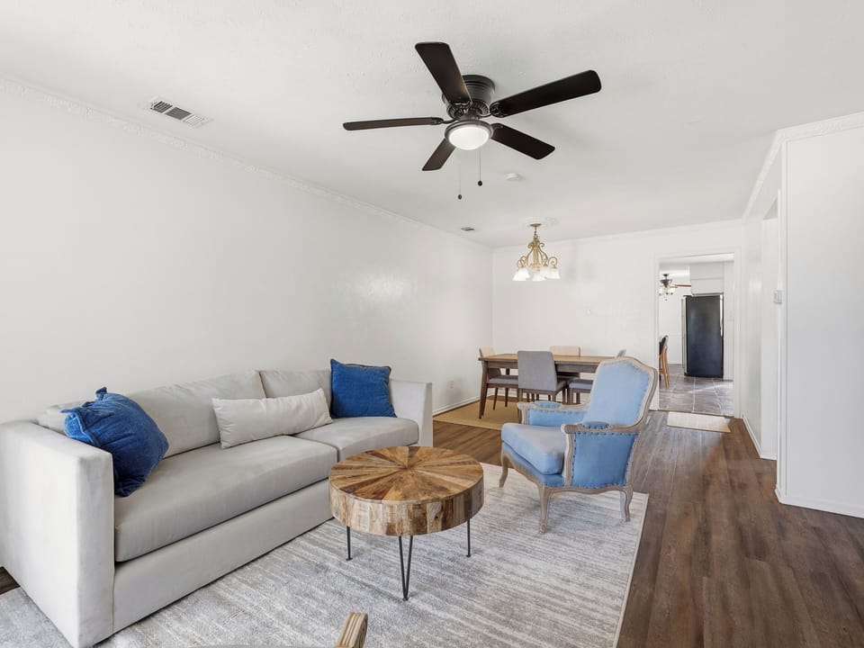 Sink into plush seating in your open-concept living and dining area, where warm wood floors and calming blue accents create a relaxed, welcoming retreat.