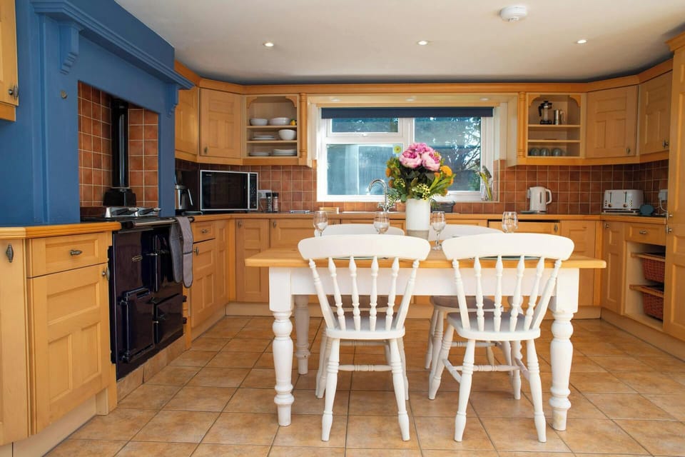 Wooden kitchen with white table and chairs, flowers in a vase