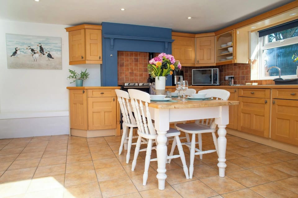 Kitchen-diner with wooden cupboards, microwave on counter and table with vase of flowers