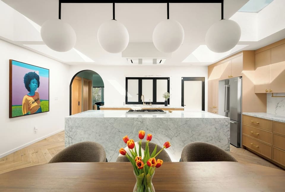 Marble waterfall kitchen with a large island and professional-grade gas range.