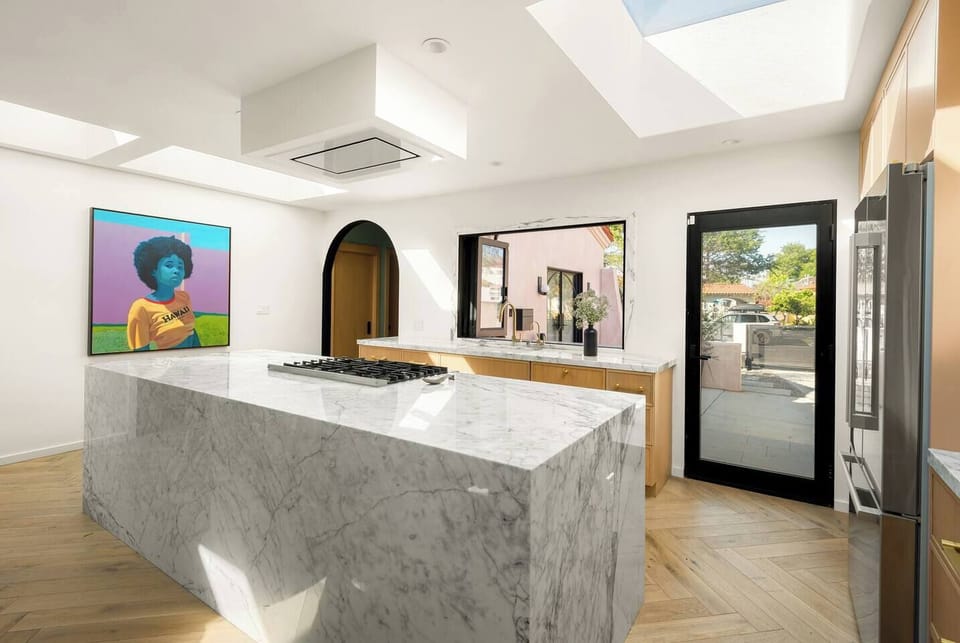 Marble waterfall kitchen with a large island and professional-grade gas range.