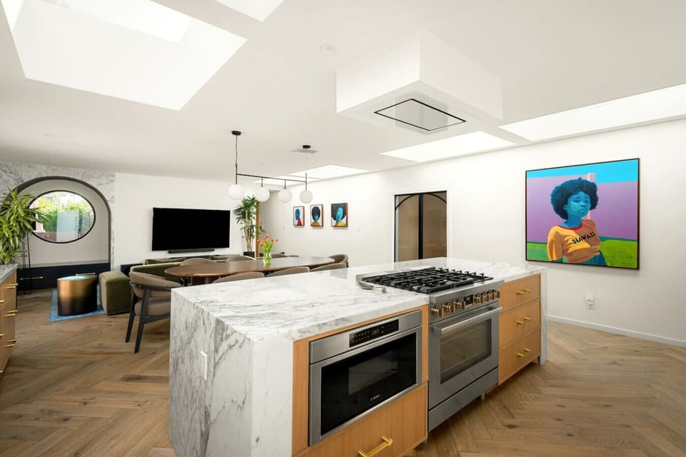 Marble waterfall kitchen with a large island and professional-grade gas range.