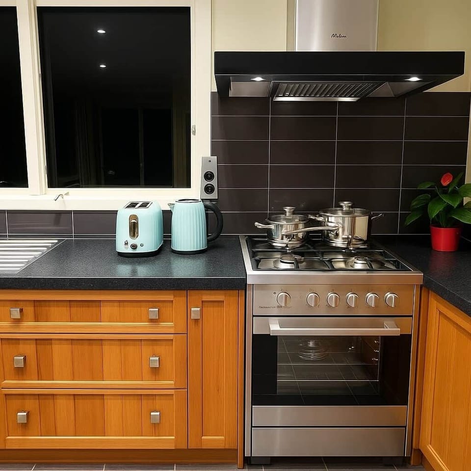Cook with ease in this well-equipped kitchen featuring a gas stovetop and oven, modern range hood, and sleek black tile backsplash.