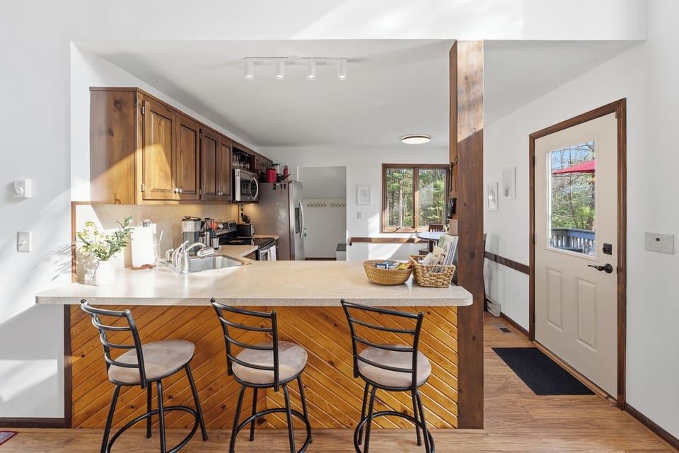 Bright kitchen with breakfast bar seating, natural light, and easy access to the deck for seamless indoor-outdoor living.