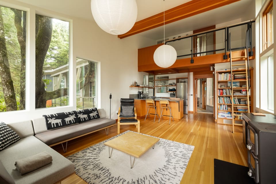 Unwind in your modern open-concept retreat with soaring ceilings, warm wood accents, and abundant natural light streaming through floor-to-ceiling windows.