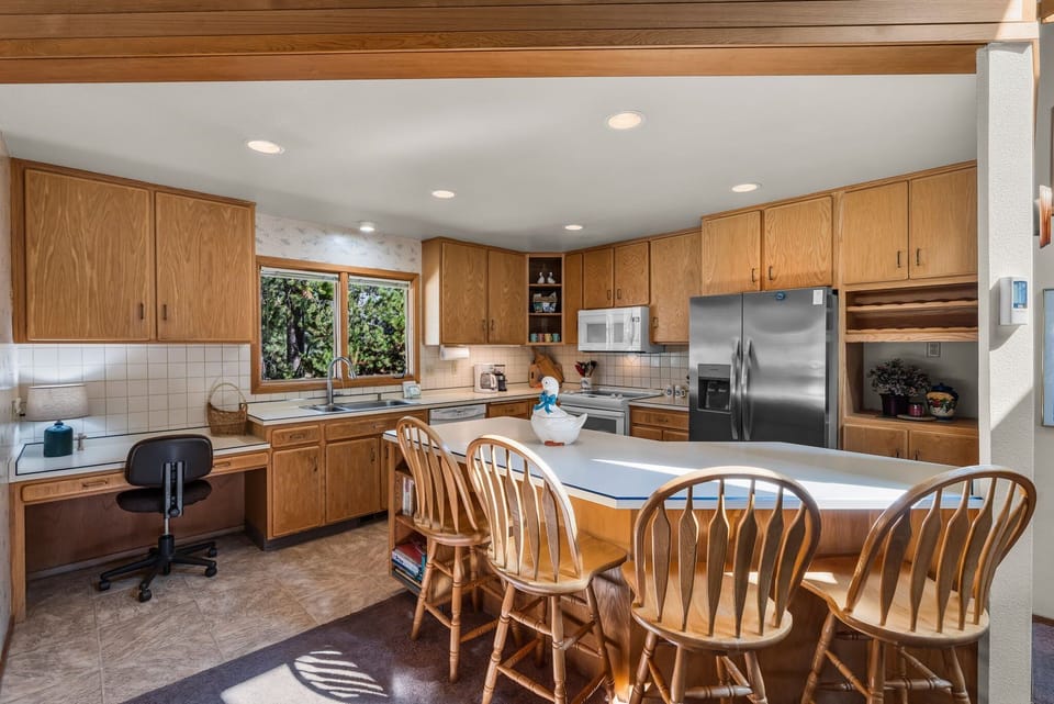 Cook together in this spacious kitchen featuring warm wood cabinets, modern appliances, and a sunny breakfast bar perfect for morning coffee.