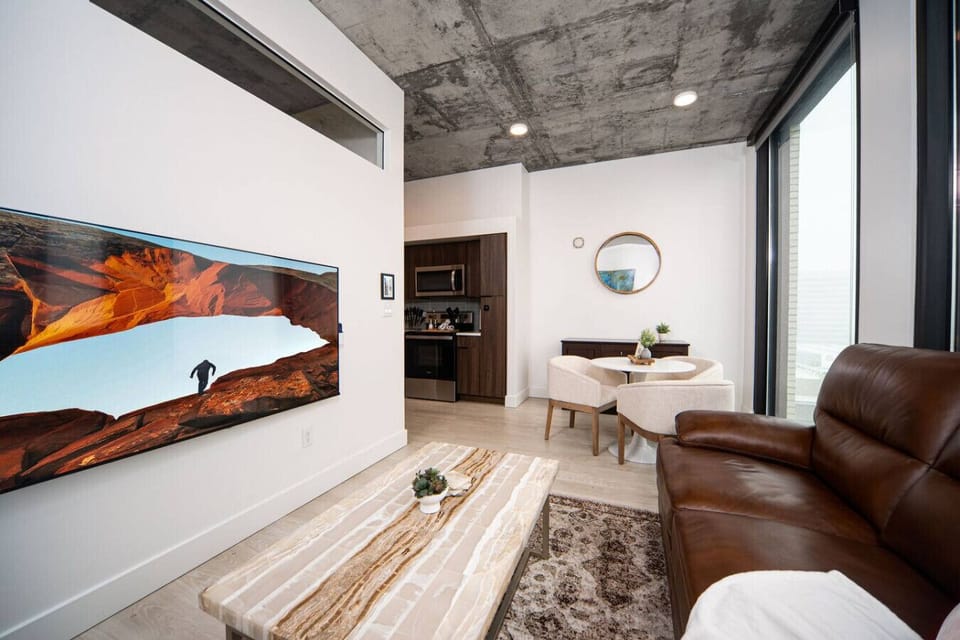 Luxury living room  with high end leather couch on the 10th floor with amazing views of downtown and mountains. Local original art and a 65” Roku tv..