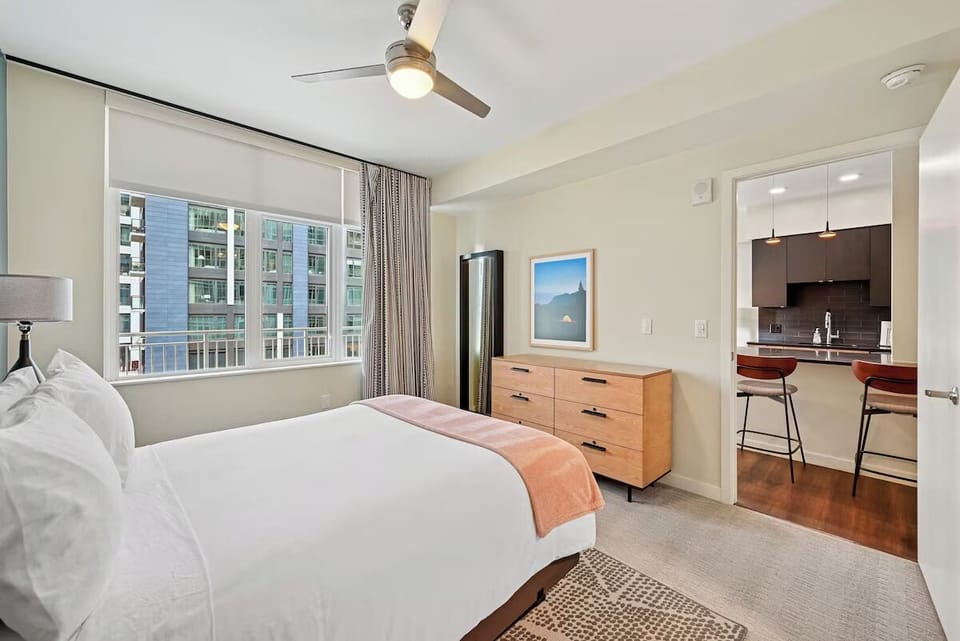 Unwind in crisp linens beside bright city-view windows.
