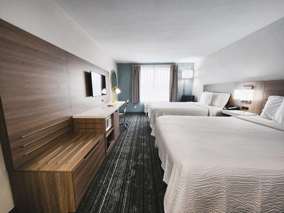 Step into an airy layout with beds, TV, and workspace.