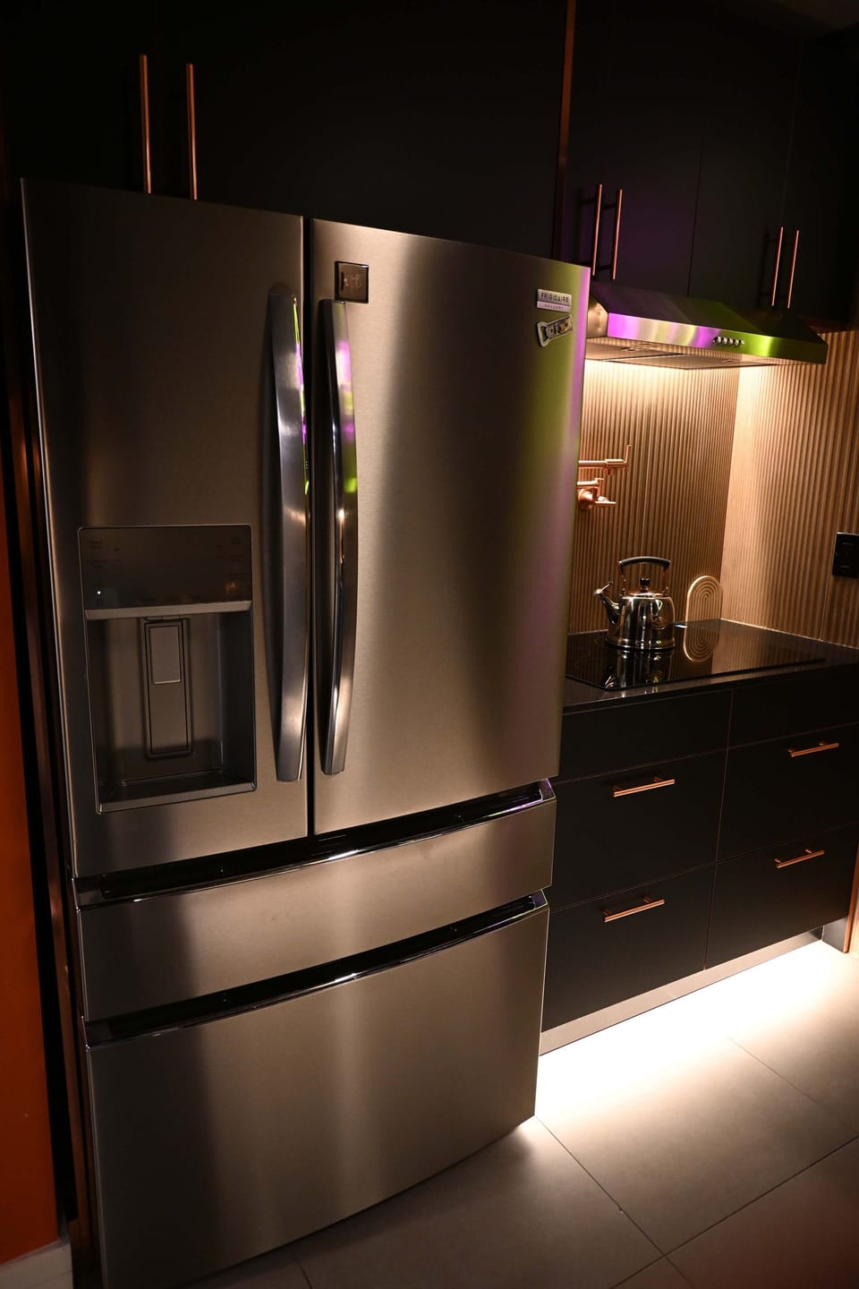 The modern kitchen features under-cabinet lighting, dark cabinetry, and premium appliances.