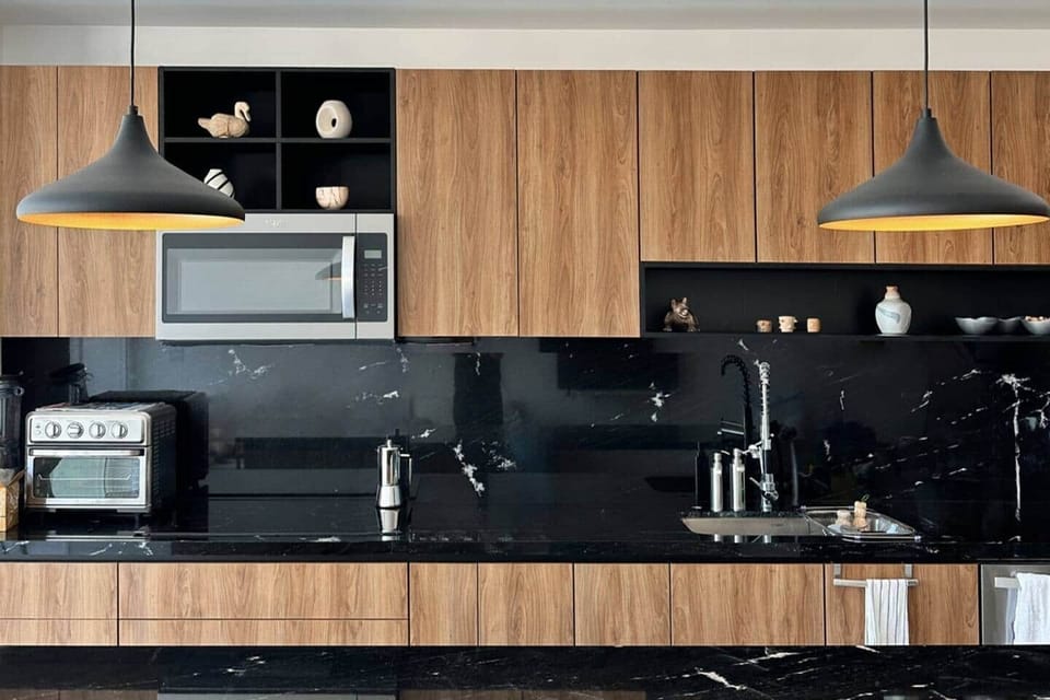 Fully equipped kitchen with filtered water, induction cooktop, air fryer/toaster, microwave, high-performance blender, food chopper, granite non-stick pots and pans, and a large sink, accented with local artisan decor.