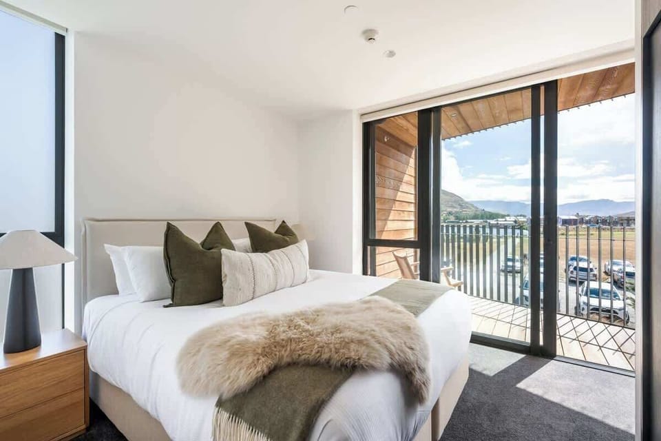 Luxury master bedroom, Clubhouse Lane apartments, Jacks Point Golf Course. King-size Sleepyhead bed, plush bedding, panoramic views of The Remarkables & Lake Tewa, modern alpine style, en-suite access. Queenstown golf & ski retreat.