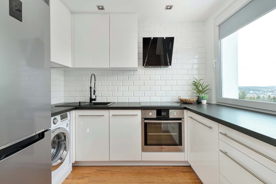A modern white kitchenette with built-in appliances and clean finishes. Functional and well-organized.
