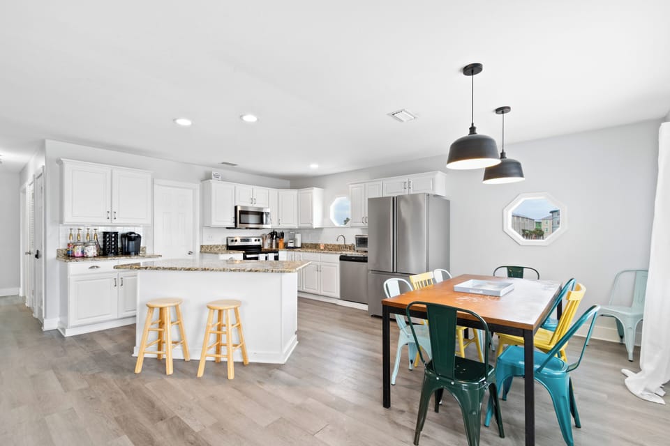 Sunny kitchen with granite, coffee bar, and seating for six at a vibrant table.