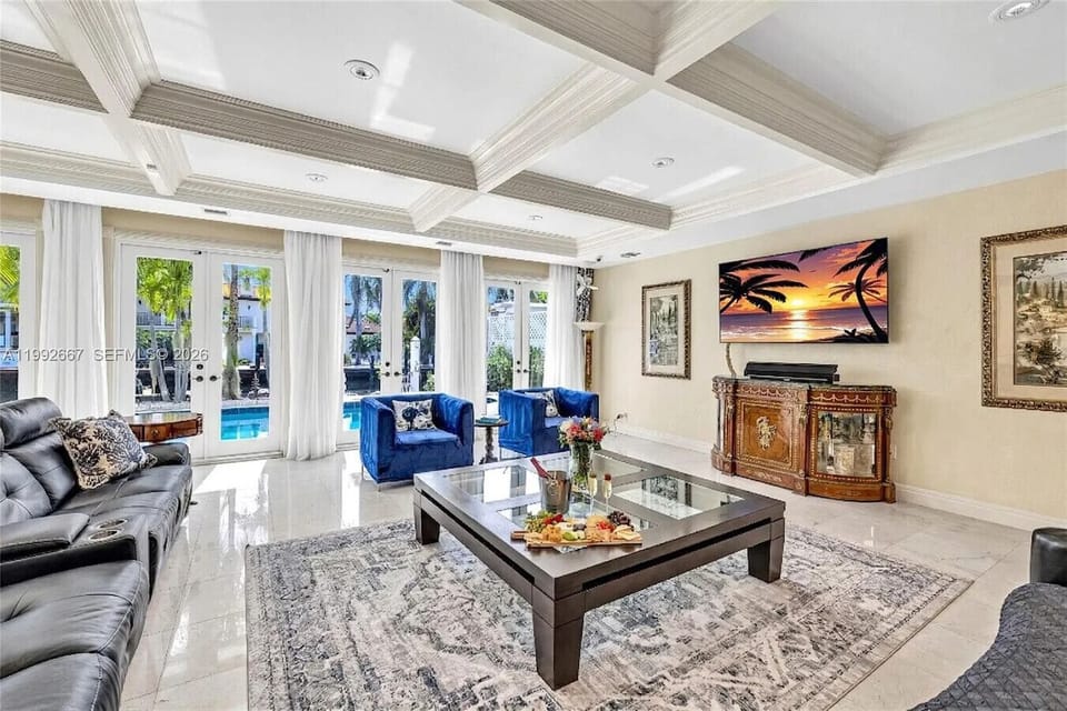 Contemporary lounge featuring ample leather sofas, a designer palette and glass-front doors opening to the pool