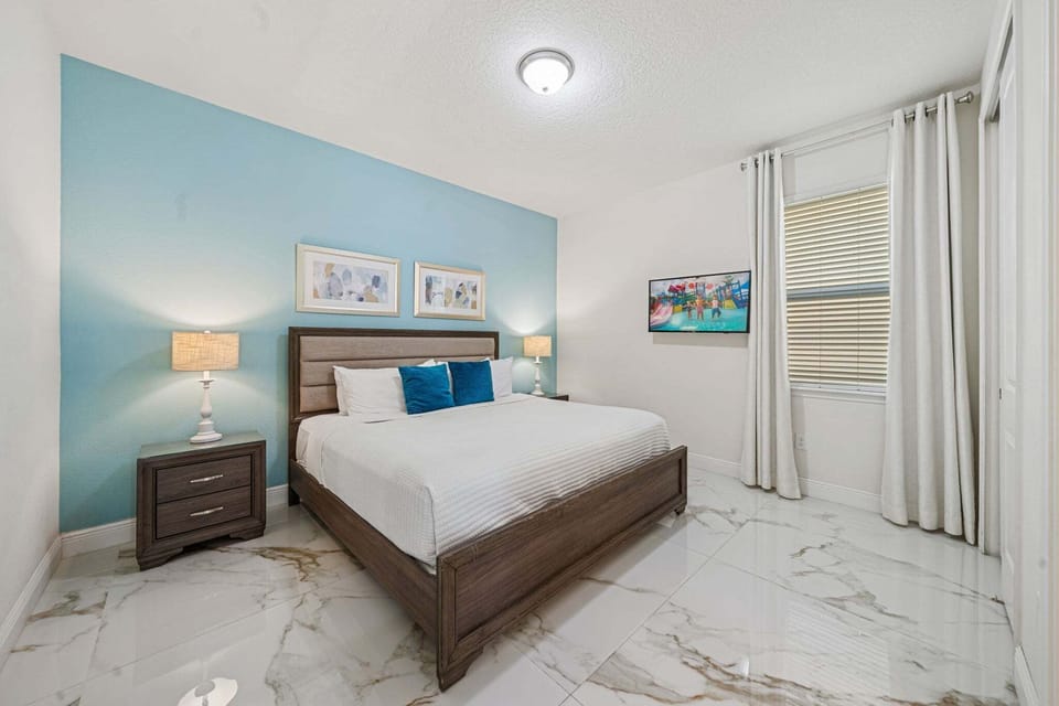 Rest easy in a serene bedroom w/ soft blue tones, plush bedding & simple decor