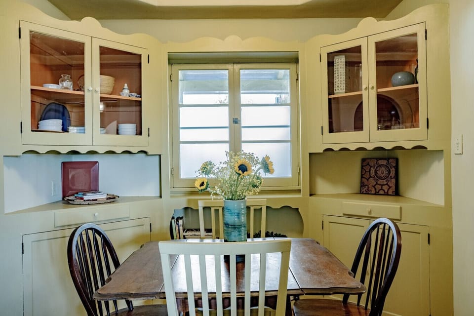 Charming dining nook with built-in cabinetry and garden views — a cozy spot for home-cooked meals during your stay.