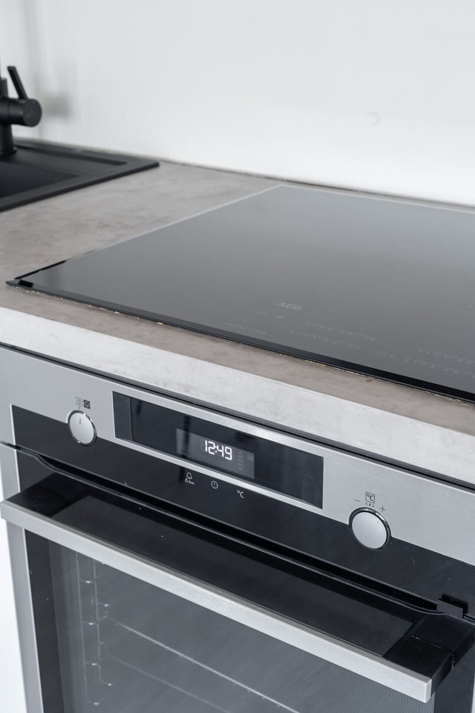Chef-ready appliances. Featuring a high-end AEG induction cooktop and integrated oven, seamlessly built into a stylish concrete-finish countertop