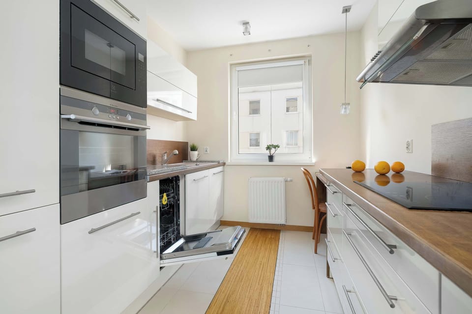 An open dishwasher is visible in this kitchen shot, showcasing the practical amenities available in the unit. The layout is optimized for a workflow between the sink, stove, and storage.