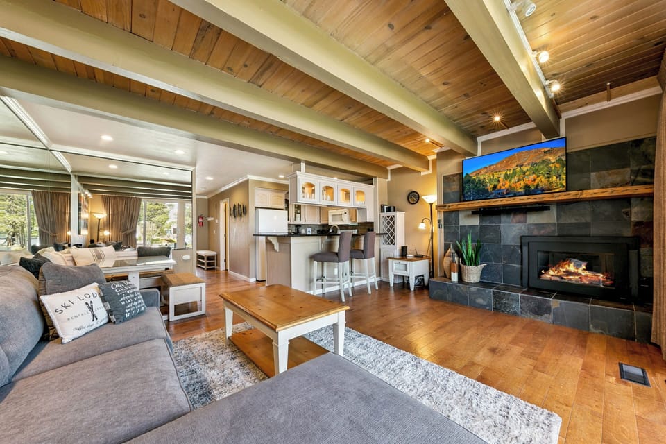 Sink into cozy sectional sofas in your open-concept living space, where vaulted wood ceilings and a crackling fireplace create the perfect retreat after a day exploring.