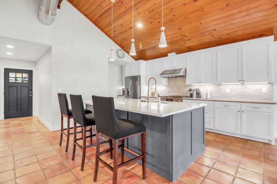 You'll love cooking in this spacious kitchen with its gleaming white countertops, modern appliances, and charming wood ceiling that adds warmth to your culinary adventures.