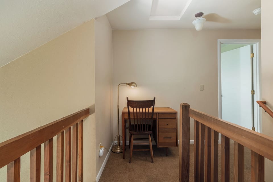 Find your perfect work-from-home spot in this quiet loft workspace, complete with wooden desk and warm lighting for productive mornings.