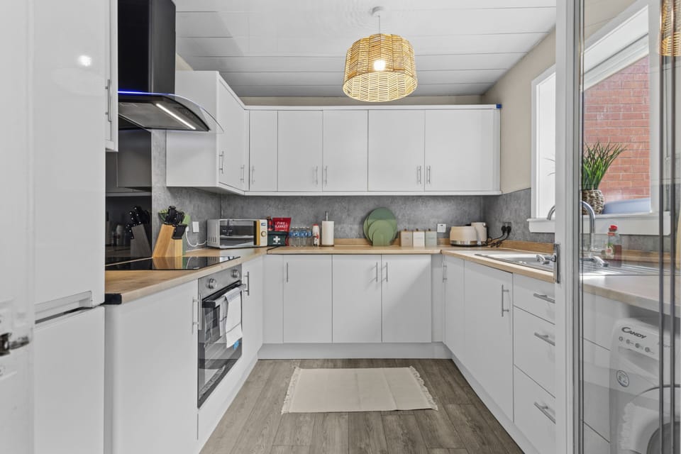 Kitchen with washing machine, microwave, kettle, oven and hob, fredge/freezer