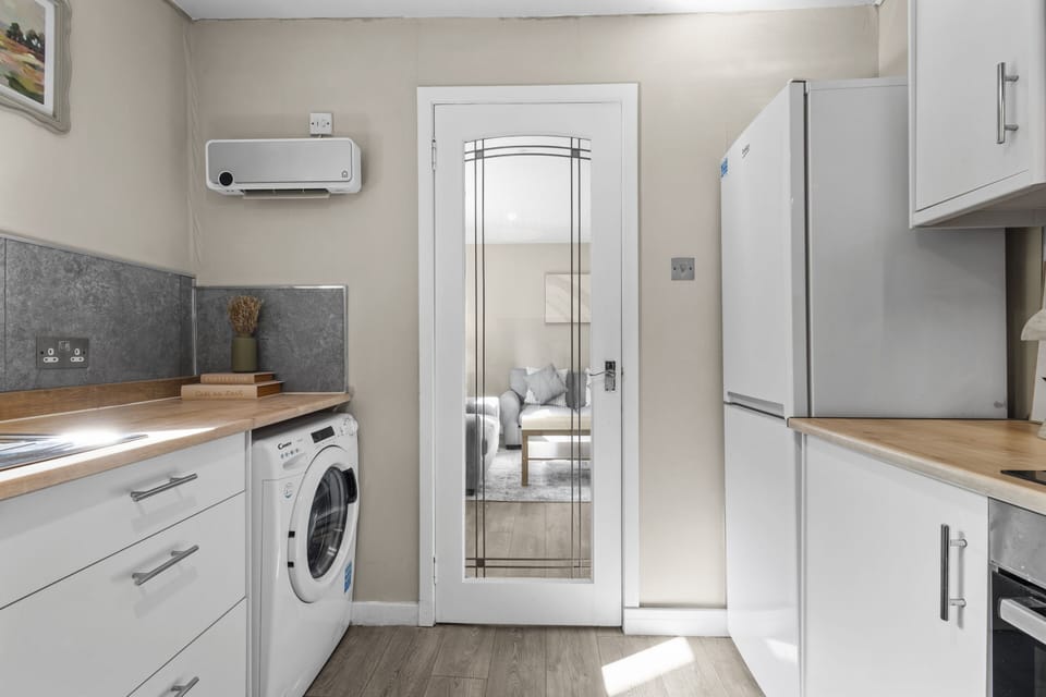 Kitchen with washing machine, microwave, kettle, oven and hob, fredge/freezer