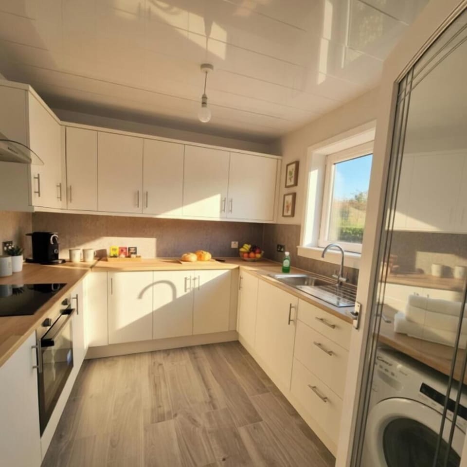 Kitchen with washing machine, microwave, kettle, oven and hob, fredge/freezer