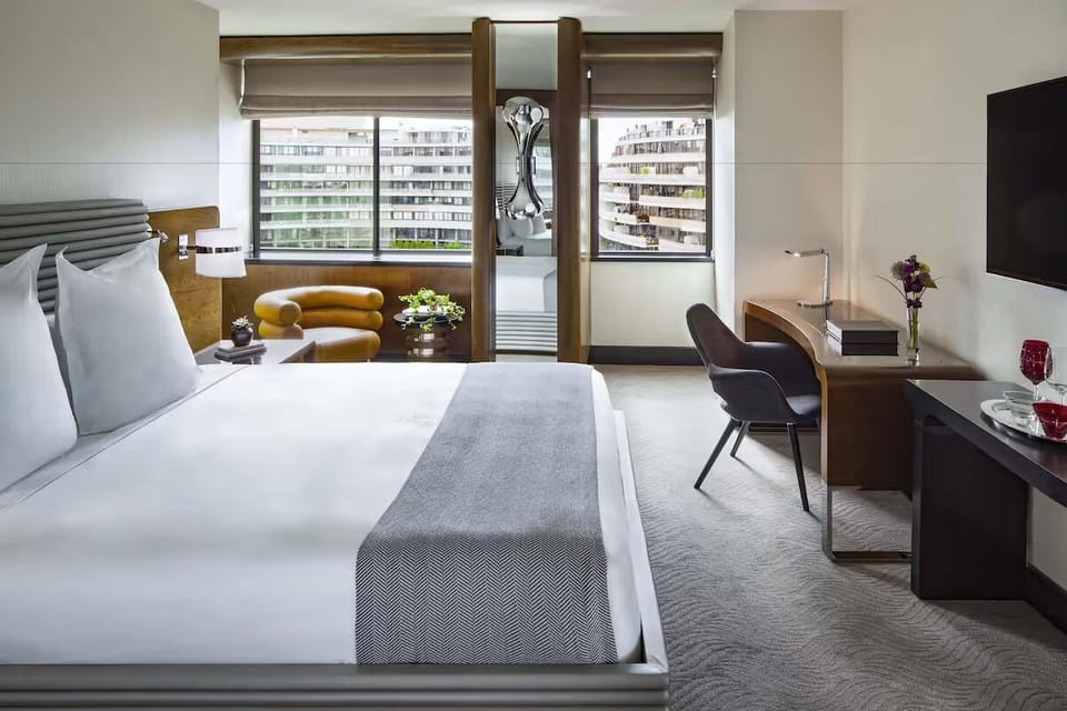 Unwind in a bright bedroom with skyline views and plush bedding.