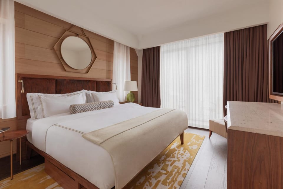 Sink into a serene king bed beside sunlit, floor-to-ceiling drapes.