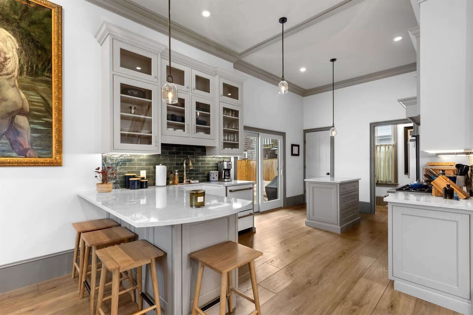This light filled kitchen offers a large island, generous prep space, custom cabinetry, and direct access to the outdoor area.