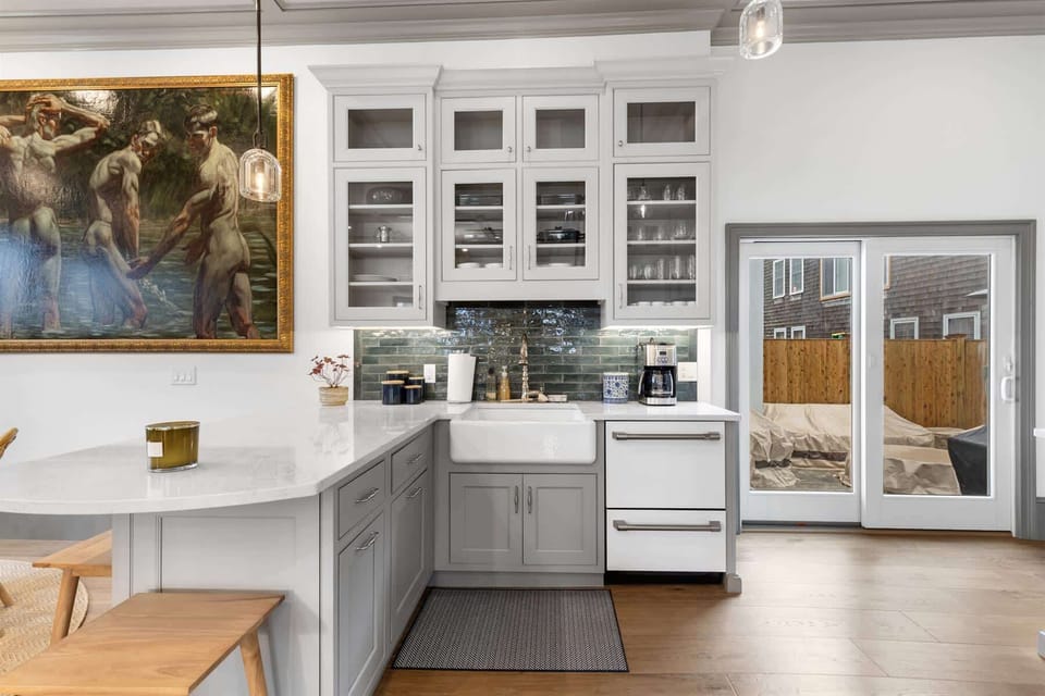 A farmhouse sink, sleek counters, and glass front cabinetry make this kitchen both beautiful and practical.