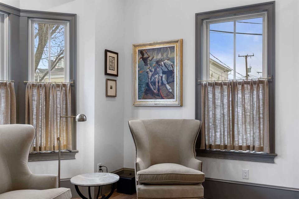 Charming art details and tall windows add warmth and personality to this quiet corner of the living room.