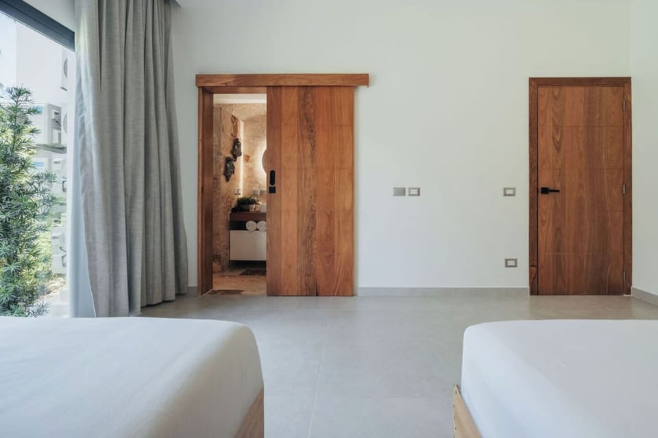 Bedroom 2 offers two double beds, ample space, and a private bathroom entrance.