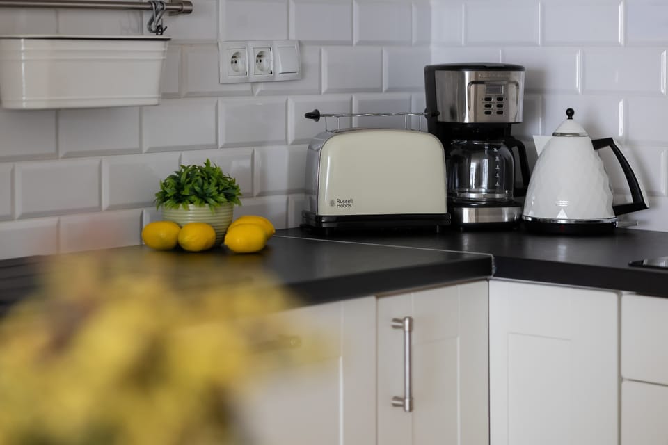 A kitchenette detail featuring appliances like a kettle and coffee machine on the countertop. Practical equipment is neatly arranged for everyday use.