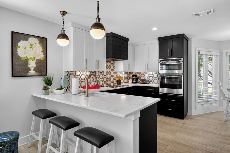 A gourmet kitchen featuring white quartz countertops, a bold geometric tile backsplash, and sleek dark cabinetry.